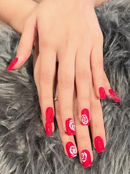 A bold red set with intricate white rose art on the accent nails. This is a classic and romantic design.