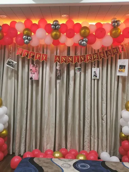 A lovely anniversary decoration in front of a window. We created a balloon garland at the top, two balloon pillars, and hung photos from the garland to add a personal touch.
