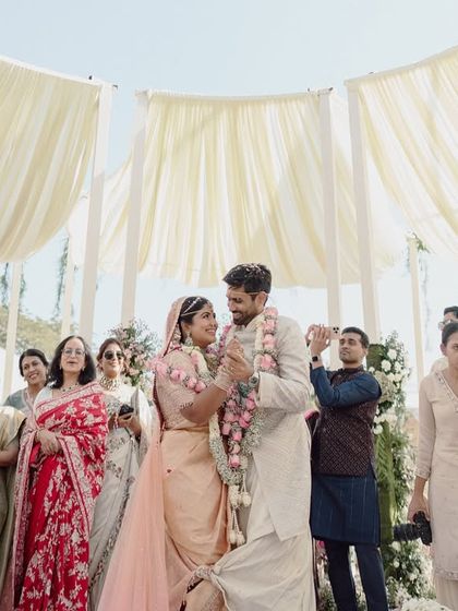 A beautiful moment during the jaimala ceremony. The circular canopy of draped fabric above creates a soft, ethereal light, making the moment feel even more special.