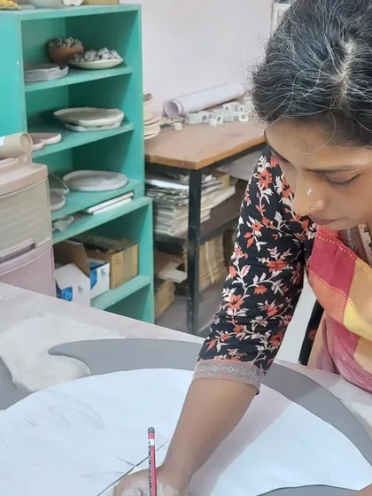 Here is my student Sukanya again, this time sketching her design onto the clay slab for her large fish mural. Planning a large piece like this takes time and vision, and it's a crucial step in the ceramic art process.