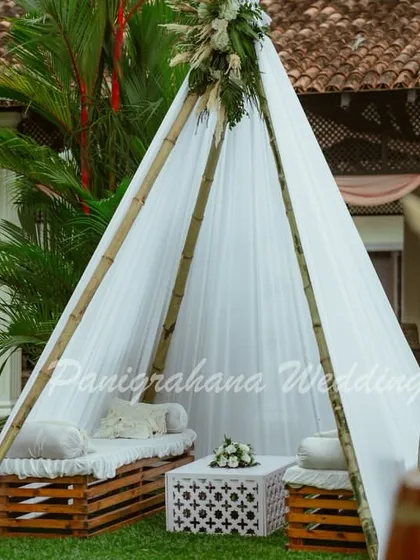 A minimalist boho teepee seating for a Mehendi, using a simple white tent, crate seating, and a peacock chair for a chic, understated look.