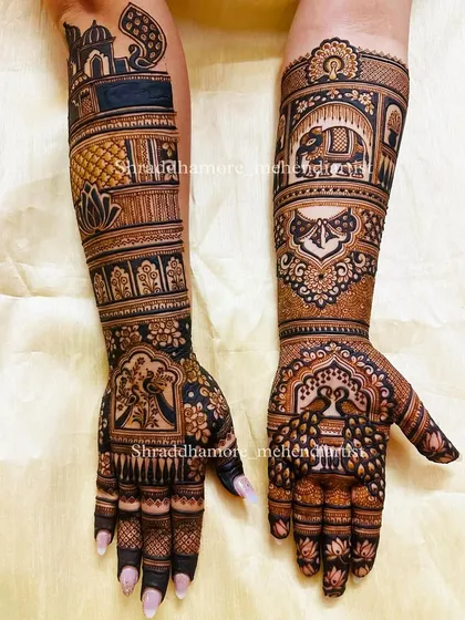 This design combines geometric patterns with traditional figures. It features a checkered pattern on one arm and elephants within arches on the other, with peacocks on both palms.