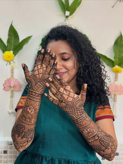 A playful shot of the bride hiding behind her beautifully decorated hands.