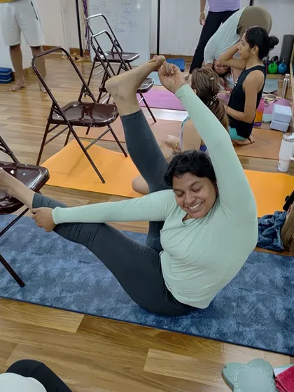 The joy of progress. This student is smiling through a challenging hip opener, showing that the journey is just as important as the final pose.
