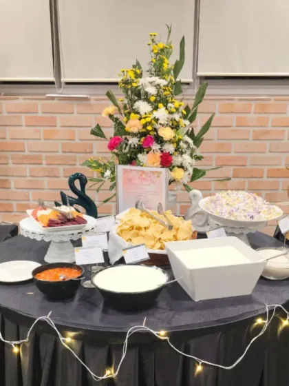 A beautifully decorated buffet table at a corporate event. We use fairy lights and floral arrangements to enhance the presentation of our food, creating a festive atmosphere.