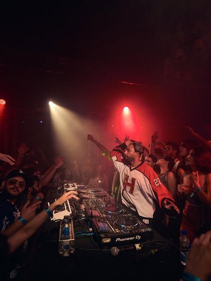 Another powerful shot from a Boiler Room set, with hands in the air and a spotlight on the decks.