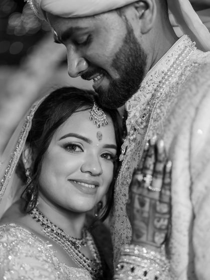 An intimate black and white close-up, showcasing the bride's beautiful henna and the couple's gentle connection.