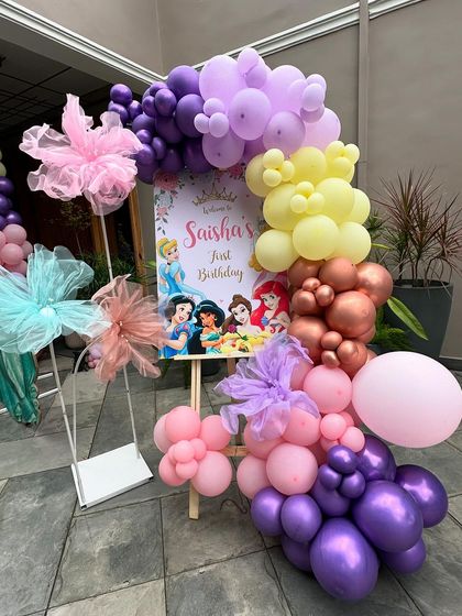 A welcome sign for the princess party, featuring illustrations of various Disney princesses and a beautiful balloon arrangement.