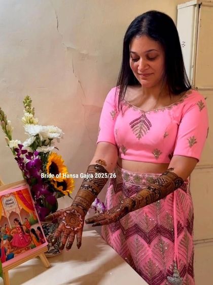 A bride admiring her freshly done mehendi. Her pink outfit and the traditional art on her hands create a look of pure elegance and happiness.