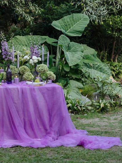 The full view of the romantic tablescape, set against a backdrop of large, lush green leaves.
