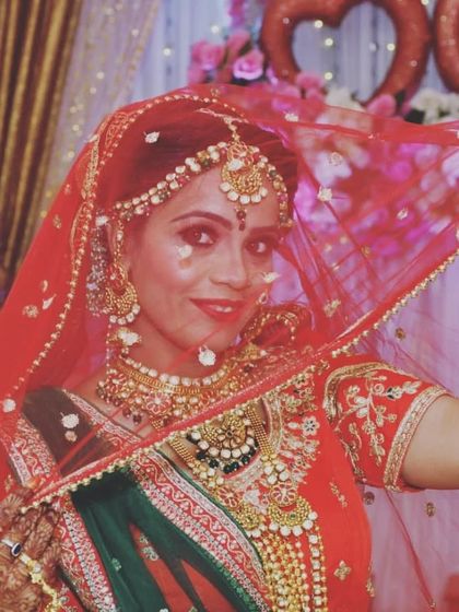 A classic bridal shot with the veil. The layered necklaces and maang tikka sparkle through, creating a truly magical effect.