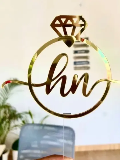 This unique engagement ring topper can be customized with your initials, like the 'h' and 'n' shown here. It's a stylish and symbolic piece for your engagement party cake.