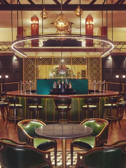 For the Karnataka Golf Association's bar, I designed a lighting scheme to create a sophisticated and moody atmosphere. This central view highlights the custom ring light fixture over the bar, which acts as a modern centerpiece, while carefully placed downlights make the green leather chairs and checkered floor pop.