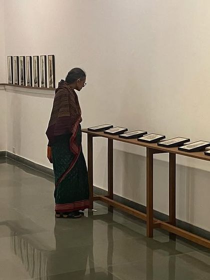 Another visitor studies the small, displayed artworks, each telling its own quiet story.