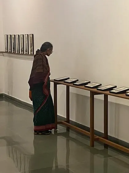 A visitor examining the row of reverse paintings, each telling a part of a larger story.
