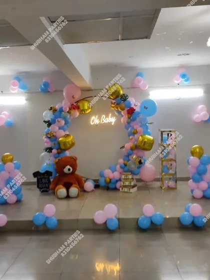 A cute "Oh Baby" shower decoration with a teddy bear prop and pink and blue balloons.