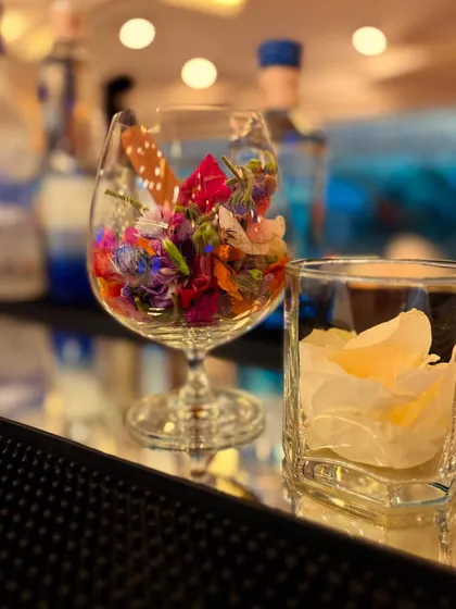 A glass filled with colorful edible flowers, ready to be used as a beautiful and delicate garnish for our signature cocktails.