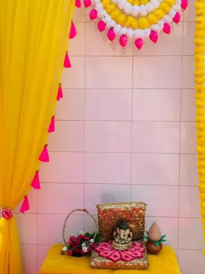 This decoration combines a bright yellow drape with pink tassels and an arch of white and yellow marigold flowers. It's a simple, budget-friendly option that still brings a wonderful festive and traditional feel to your home puja space.