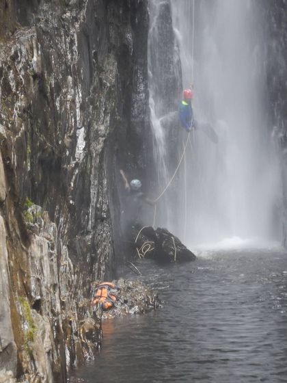 Managing ropes and gear in the middle of a multi-pitch waterfall is a key skill. Here you can see our team operating from a small stance mid-descent.