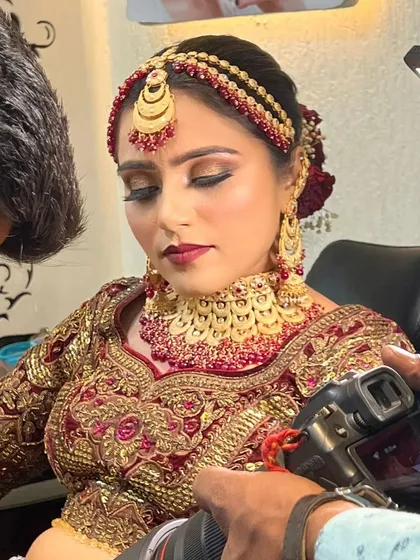 A behind-the-scenes shot during the getting-ready process. You can see the camera capturing the intricate details of the matha patti and the perfectly blended eye makeup.