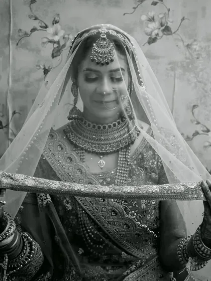 A classic black and white bridal portrait, with the bride gently holding her veil, creating a look of timeless elegance.