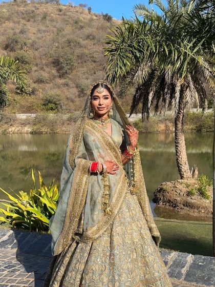 The bride in a serene outdoor setting, her traditional Sabyasachi outfit and simple, elegant braid looking perfect against the natural backdrop.
