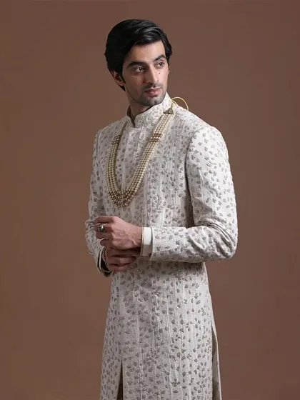 A closer view of the ivory sherwani, highlighting the subtle texture and intricate handwork. This modern fusion allows for both comfort and elegance.