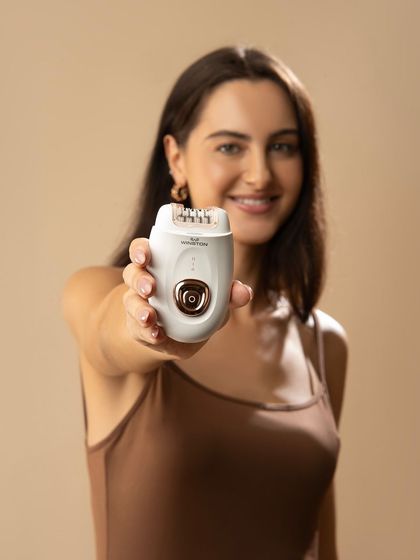 A confident shot of the model presenting the epilator to the camera. This builds trust and highlights the product as the hero.