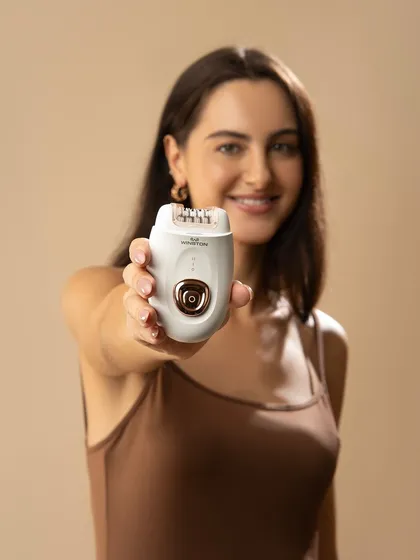 A direct-to-camera shot where the model presents the epilator. This builds a connection with the viewer and puts the product front and center, highlighting its ergonomic design and sleek finish.