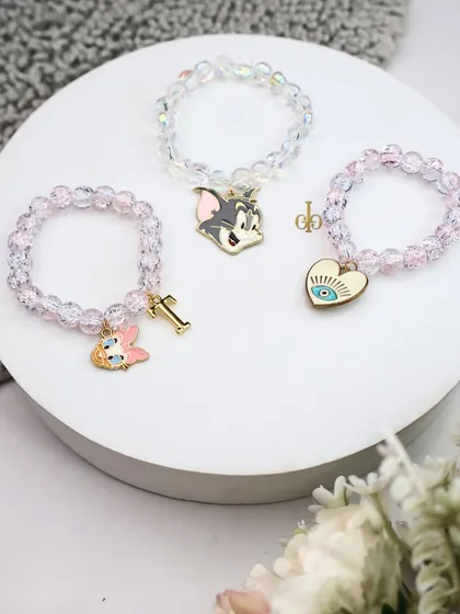 A trio of our sparkle bracelet Rakhis, featuring Tom from Tom & Jerry, a personalized initial, and an evil eye heart charm.