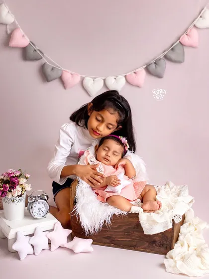 An older sister watches over her sleeping baby sibling. This quiet, tender moment is a beautiful representation of unconditional love and protection.