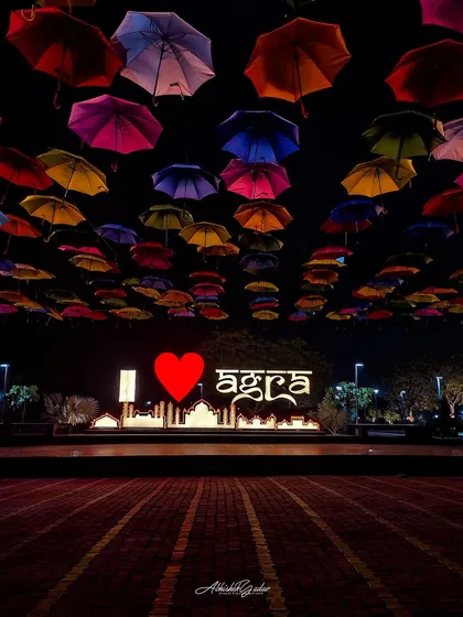 The "I Love Agra" sign with a colorful umbrella installation, captured at night. A vibrant and welcoming shot of the city's preparations for an event.