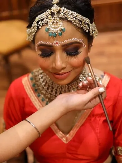 A behind-the-scenes shot of applying blush to my Bengali bride. The traditional 'chandan' art is already in place, ready for the final touches.