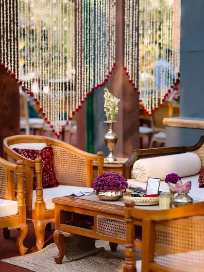 A close-up of a seating area, showing the mix of textures from the cane furniture, plush cushions, and delicate floral curtains. I focus on creating a multi-sensory experience through design.