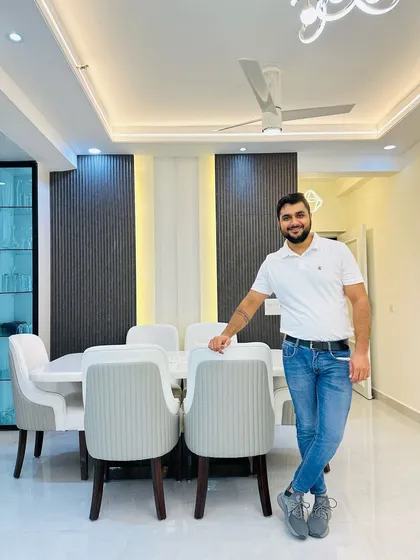 Posing in the elegant dining area, which is defined by a paneled accent wall and a modern six-seater dining table.
