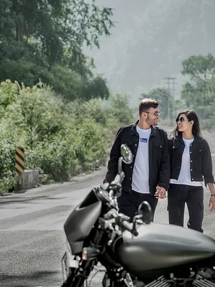 Walking hand-in-hand down a mountain road, with their bike waiting. This shot feels like a scene from a road trip movie, full of adventure and romance.