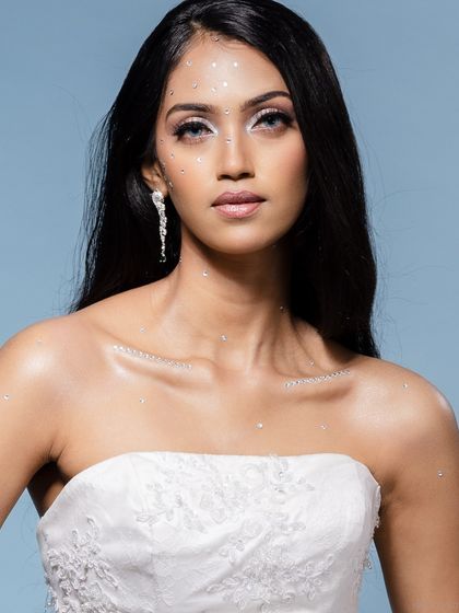 A direct-to-camera portrait of the model in the white bridal gown, with subtle glitter makeup.