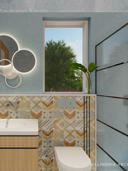 A playful yet chic bathroom design with geometric patterned tiles and soft blue walls. The round, backlit mirrors add a modern touch, while the wooden vanity brings warmth to the space.