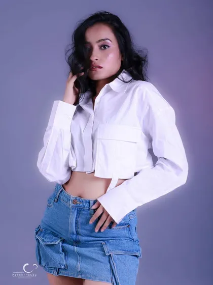 A confident and stylish pose against a soft purple background. The wind-blown hair adds a sense of movement and freedom.