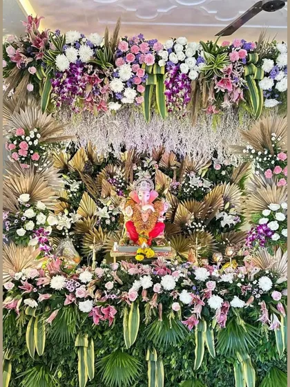 A lush and tropical Ganpati mandap, overflowing with a variety of fresh flowers and greenery. This design uses dried palm leaves and exotic blooms to create a vibrant, jungle-like paradise.