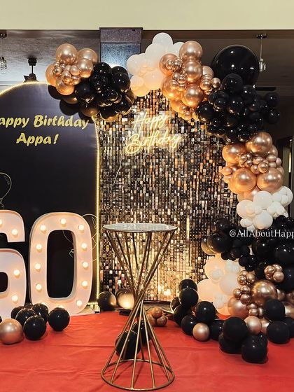 Milestone birthdays deserve to be grand. We designed this stylish black, gold, and white theme for a 60th birthday celebration at home, transforming the space with a shimmer wall, marquee lights, and a sophisticated balloon arrangement.
