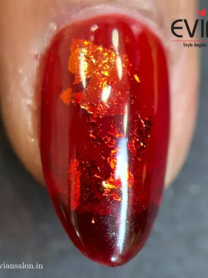 This macro shot shows a deep red jelly polish with flecks of red metallic foil suspended within. This technique gives the nail a beautiful depth and a unique, shimmering texture.