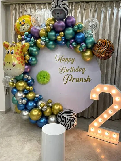 A modern jungle-themed second birthday. The setup includes a clean white backdrop, a stylish balloon arch with animal print accents, and a light-up number '2'.