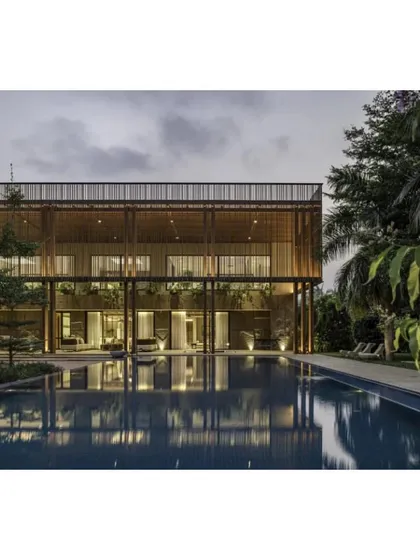 The 'K House' at dusk, where the lighting design highlights the home's layered structure and its reflection in the expansive swimming pool.