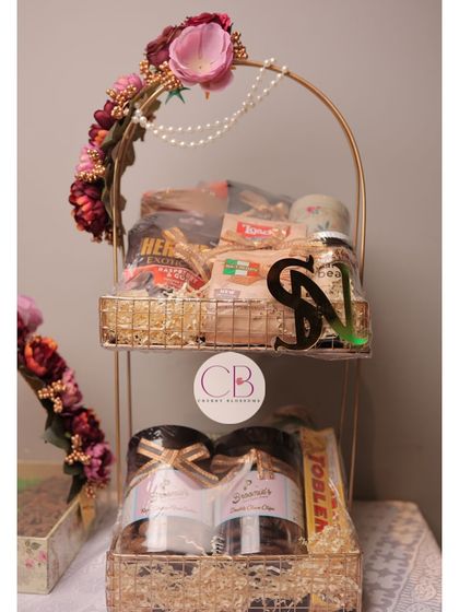 A beautiful two-tiered confectionery hamper we created for the 'ladkewalas' (groom's family). It's filled with a variety of snacks and our homemade treats, and decorated with flowers and a custom initial.