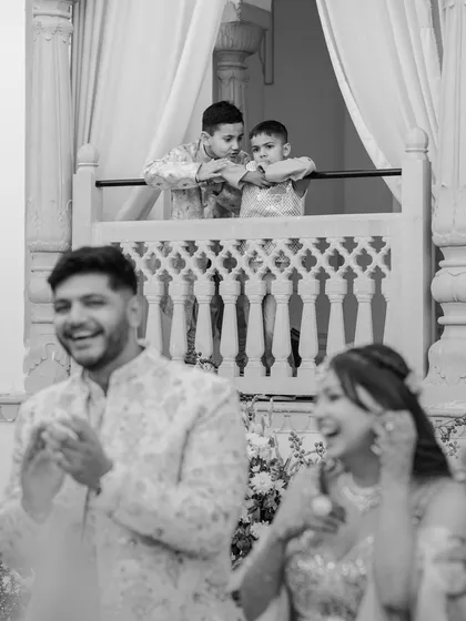 While the couple laughs below, two young boys watch the ceremony from a balcony. This shot captures a beautiful, multi-layered story happening in a single frame.