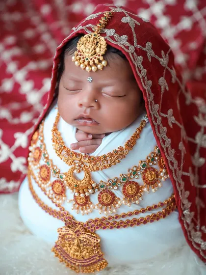 We celebrate cultural heritage with beautifully styled traditional photoshoots. This baby is adorned with intricate, baby-safe jewelry and wrapped in a rich red fabric, creating a timeless and meaningful portrait.