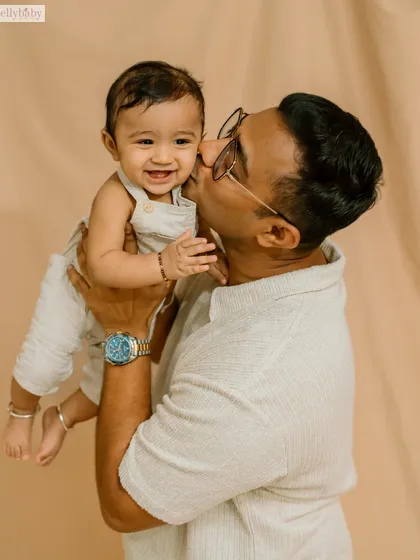 A sweet kiss on the cheek from a father to his smiling son. This simple, affectionate gesture makes for a powerful and heartwarming portrait.