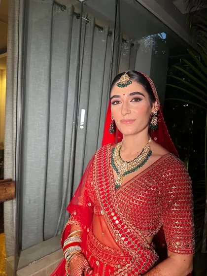 A beautiful guest in a classic red lehenga. Her makeup is soft and timeless, enhancing her natural beauty.