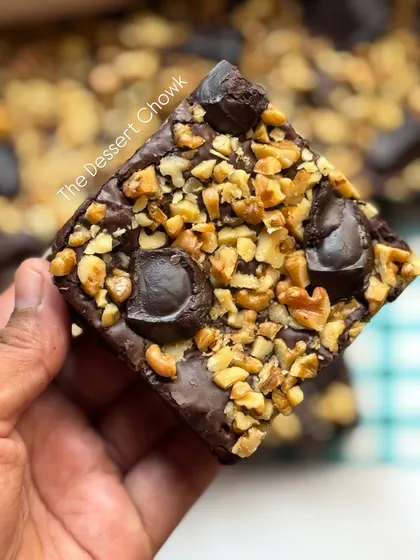 A close-up of a single walnut brownie square. You can see how it's generously topped with toasted walnuts and rich chocolate chunks.